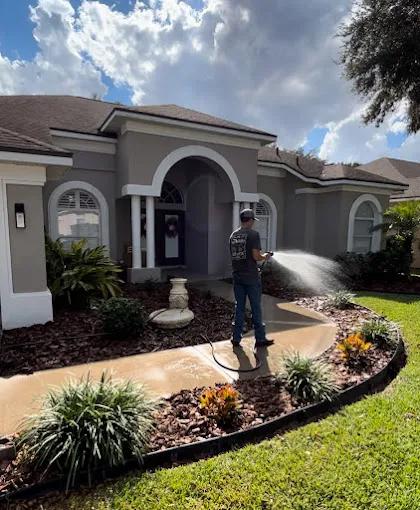 Technician adjusting irrigation spray over a front landscape bed